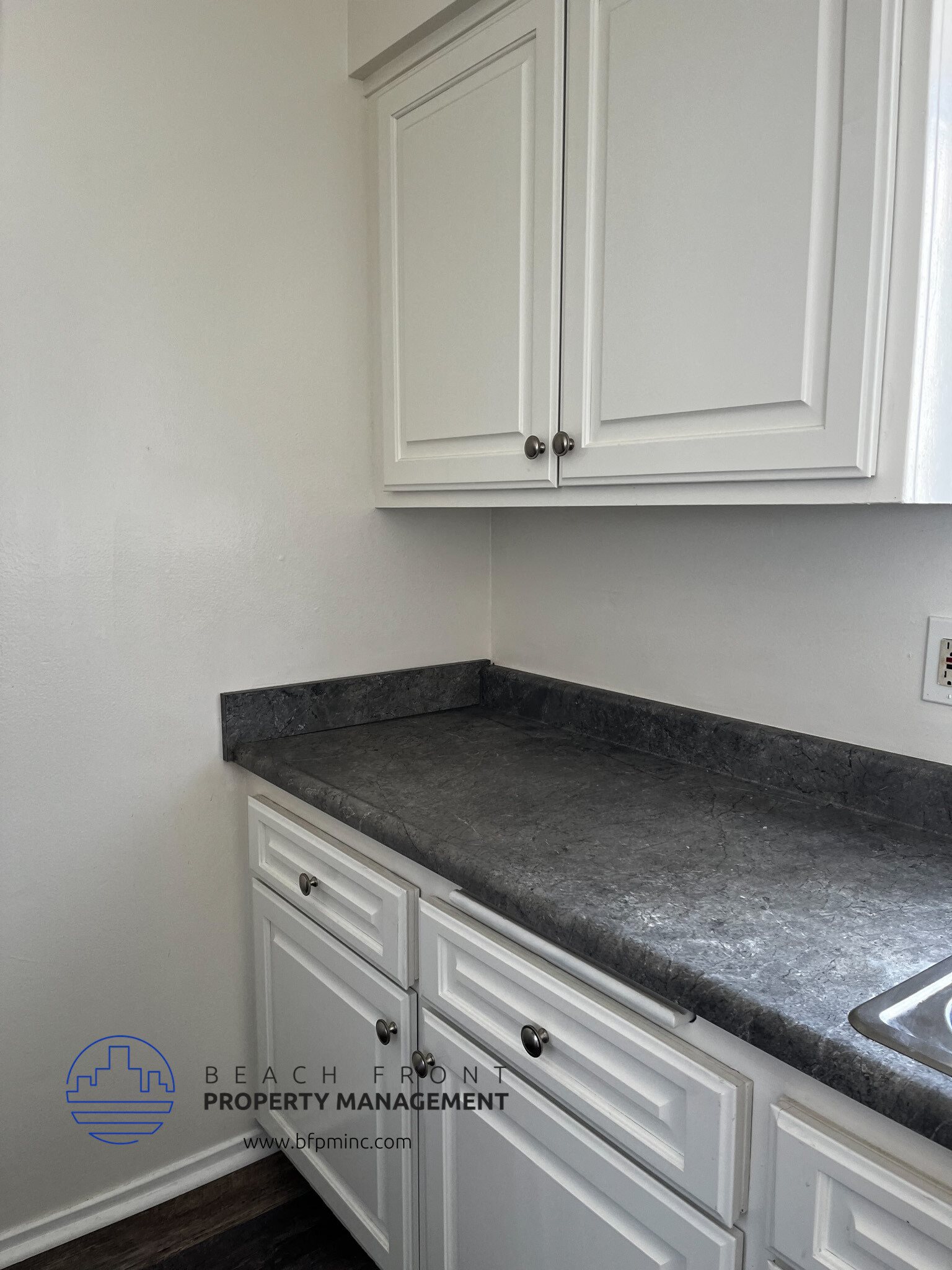 a kitchen with white cabinets and gray countertops